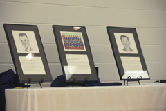 three framed photos and sketches of inductees on table