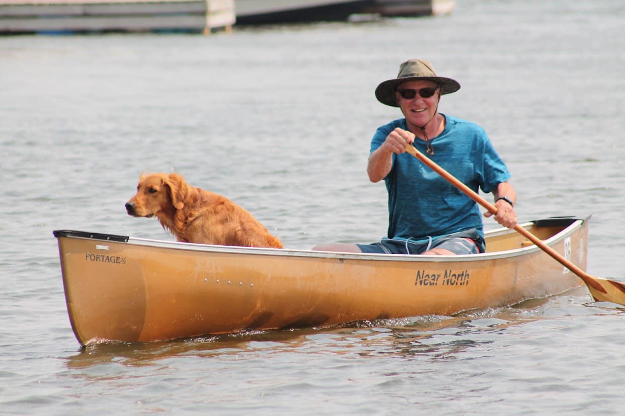 Person paddling on a canoe with a dog