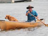 Person paddling on a canoe with a dog