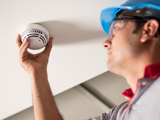 Person with PPE screwing in a smoke detector